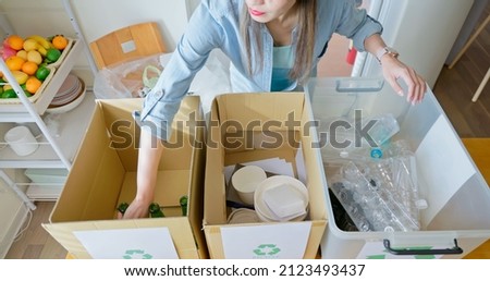 high angle view of Asian woman is separating trash and sort waste in garbage box for recycling at home