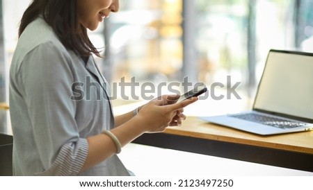 Close-up image, A female freelancer using a smartphone, searching some information, resting on social media and remote working at cafe. 