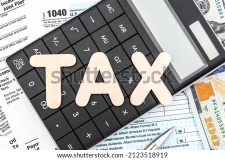 Tax concept. Word "TAX" on calculator with tax forms and money.