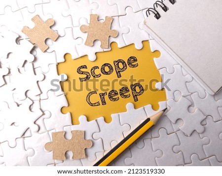Selective focus.Top view pencil and notebook with text Scope Creep on a white puzzle background. Royalty-Free Stock Photo #2123519330