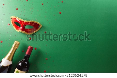 Happy Purim carnival decoration concept made from red mask, wine, and sparkle star on green background. (Happy Purim in Hebrew, jewish holiday celebrate).