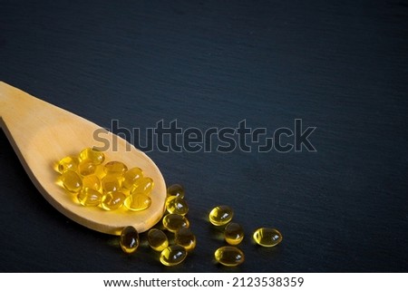 Wooden spoon of Omega-3 capsules with copyspace. wellness, health, supplements, flat lay.