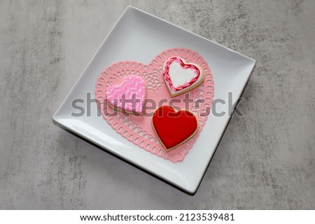 Three heart-shaped sugar cookies with royal icing for valentine's day.