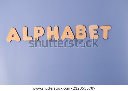 The word Alphabet made of wooden letters on a colored background