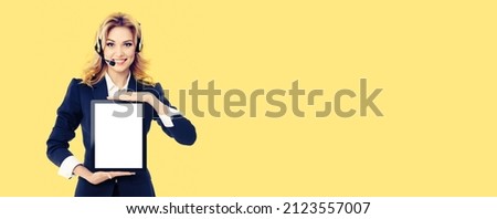 Call center. Businesswoman or female support phone operator in headset, showing mock up tablet pc touchpad ipad with copy space area, yellow color background. Customer service centre help consulting.