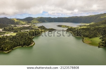 Aerial view of calm volcanic pond surrounded by green trees in mountains in Sete Cidades