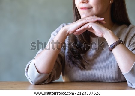 Closeup image of a beautiful young woman sitting with chin resting on hands
