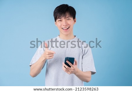 Young Asian man using smartphone on blue background Royalty-Free Stock Photo #2123598263