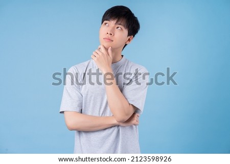 Young Asian man posing on blue background Royalty-Free Stock Photo #2123598926