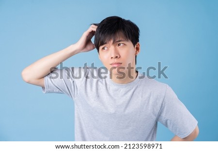 Young Asian man posing on blue background Royalty-Free Stock Photo #2123598971