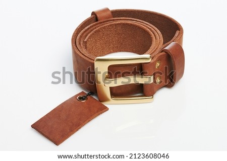 New brown color leather belt with tag rolled isolated on studio background