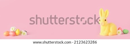 Easter bunny, eggs and flowers on pink background with space for text