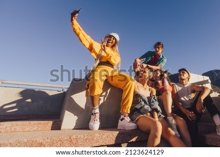Vibrant young people taking a selfie together outdoors. Happy youngsters enjoying hanging out together in the city. Group of generation z friends capturing their happy moments. Royalty-Free Stock Photo #2123624129