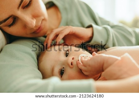 Mother cuddling her newborn baby on the bed. Closeup of an affectionate young mother caressing her baby. New mom creating a bond with her infant child. Royalty-Free Stock Photo #2123624180