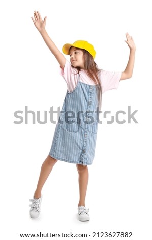 Adorable little girl in pinafore dancing on white background