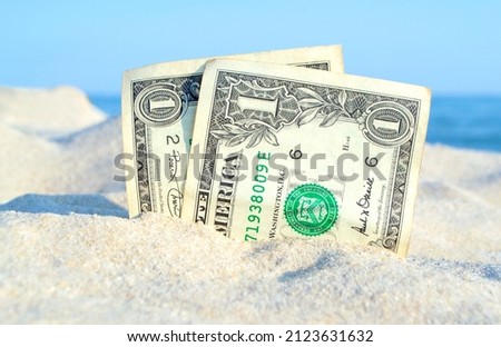 Two old dollar bills in sand on background of sea blue sky on sunny summer day. Dirty dollars close-up. Money grows from sand. Abstract concept money business pay finance vacation rest travels tourism