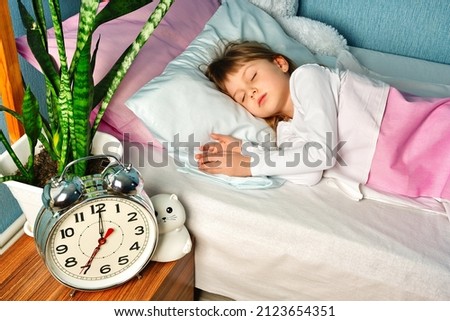 Girl schoolgirl sleeps in pajamas in the bedroom on the bed in the morning. The concept of the correct life schedule