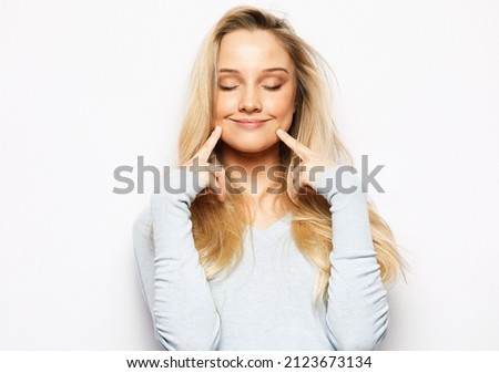 Beautiful young blond woman touching soft cheek smile with clean and fresh skin Happiness and cheerful with positive emotional over white background.