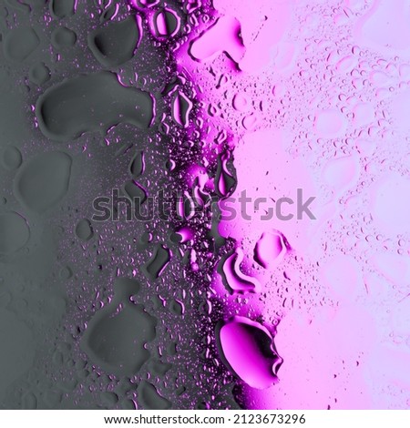 Abstract photo made by capturing shapes of oil and water mix with graduated light pink and purple colors lights. Creative neon colors background.