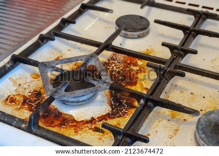 Dirty stove with food leftovers. Unclean gas kitchen cooktop with greasy spots, old fat stains, fry spots and oil splatters. Royalty-Free Stock Photo #2123674472
