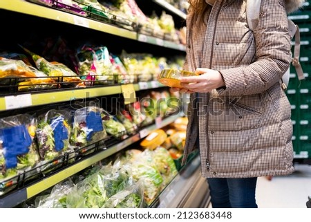 unrecognizable woman in supermarket buying vegetables and reading their nutritional information