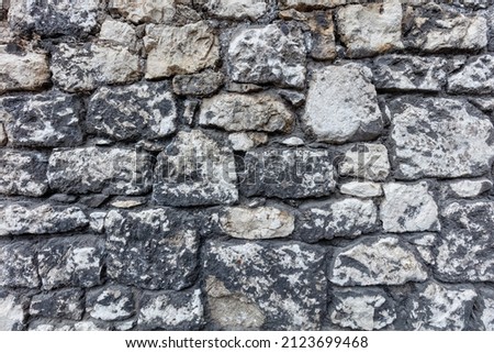 Old ruined masonry made of gray natural stone of different sizes and shapes. Background for design.