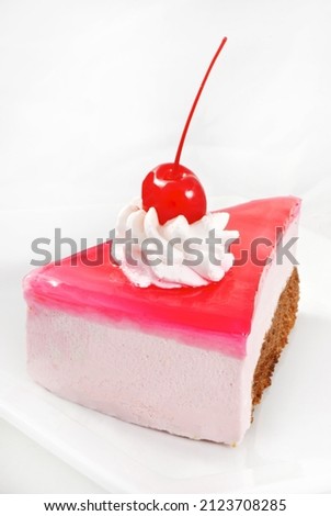 Piece of yogurt cake with cream and cherry on white background