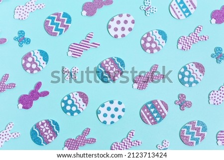 Happy Easter Pattern on blue. Decorative rabbits and eggs in rows. Paper cut glitter and sparkling colorful decorated Easter eggs, bunnies and butterflies with shadows.