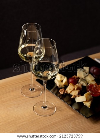 Cheese mix plate with glass of wine on table in restaurant interior black background for romantic atmosphere and celebration  Royalty-Free Stock Photo #2123723759