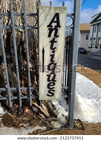 A sign that indicates there are antiques being sold. There is an arrow pointing in the direction of where the antique shop is located.