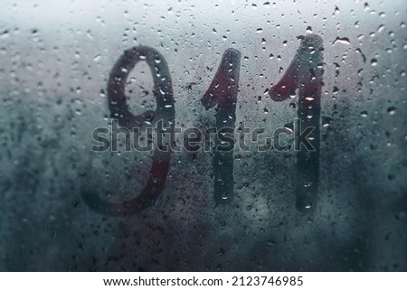911 written on wet fogged glass on a rainy day