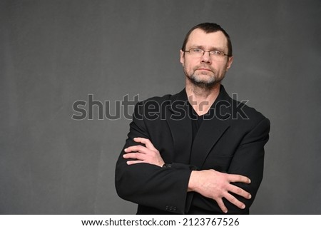 Portrait of a business man in glasses with crossed arms on a gray background