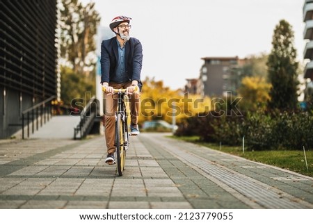 Successful middle-aged businessman riding bicycle on his way to work through the city.