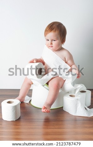 Handsome toddler and toilet paper rolls with potty. Potty training.