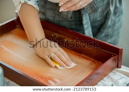 Restoration of furniture, women's hands skin the wooden surface