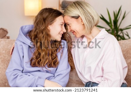 Smiling loving young Caucasian mother relax on couch with teen daughter chat and talk. Happy caring mom rest on sofa with teenage girl child, enjoy good leisure family weekend together Royalty-Free Stock Photo #2123791241