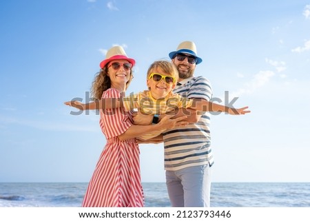 Happy family having fun on the beach. Mother and father holding son against blue sea and sky background. Summer vacation concept Royalty-Free Stock Photo #2123793446
