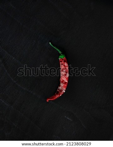 Frozen dried chilly pepper on a black textured background