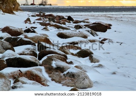 Sea coast with stones covered with frozen snow, unfocused background. High quality photo