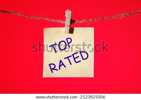 top rated text on a yellow sticker on a rope with clothespins on a red background.