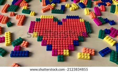 Photo of a heart made from a children's constructor with a pixel art technology lies on the table