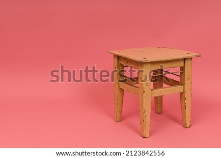 old wooden stool on pink background with copy space