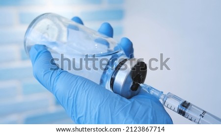 A doctor or nurse in blue medical gloves dials medicine into a syringe. Health doctor dials the vaccine into a syringe close up.