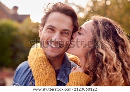 Portrait Of Happy Loving Couple With Woman Giving Man Kiss On The Cheek