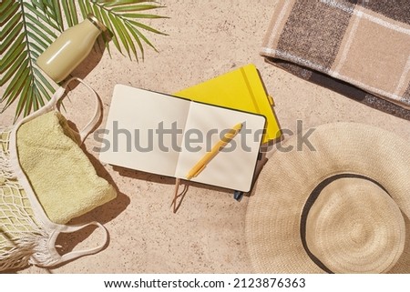 Summer sunny beach concept flat lay.Hat, string bag with towel and bottle, palm leaves, accessories and notepad. High quality photo