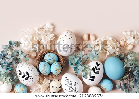 Easter eggs with sweets and flowers on beige. Happy Easter concept. White and blue eggs and cute nest with candy  Royalty-Free Stock Photo #2123885576