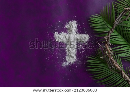 Lent border of cross of ashes, palm leaves and crown of thorns on a dark purple background Royalty-Free Stock Photo #2123886083