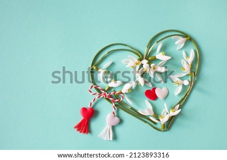 Green and turquoise background with a heart of snowdrops and red and white lace with tassels. Postcard for the holiday on March 1, Martisor, Baba Marta. Royalty-Free Stock Photo #2123893316