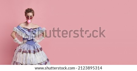 Funny lady. Vintage portrait of young adorable girl in image of medieval royal person in renaissance style dress isolated on pink background. Comparison of eras, beauty, history, art, creativity. Royalty-Free Stock Photo #2123895314