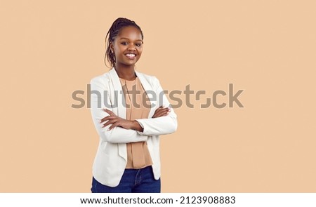 Studio portrait of happy successful confident black business woman. Beautiful young lady in white jacket smiling at camera standing isolated on blank solid beige colour copyspace background Royalty-Free Stock Photo #2123908883